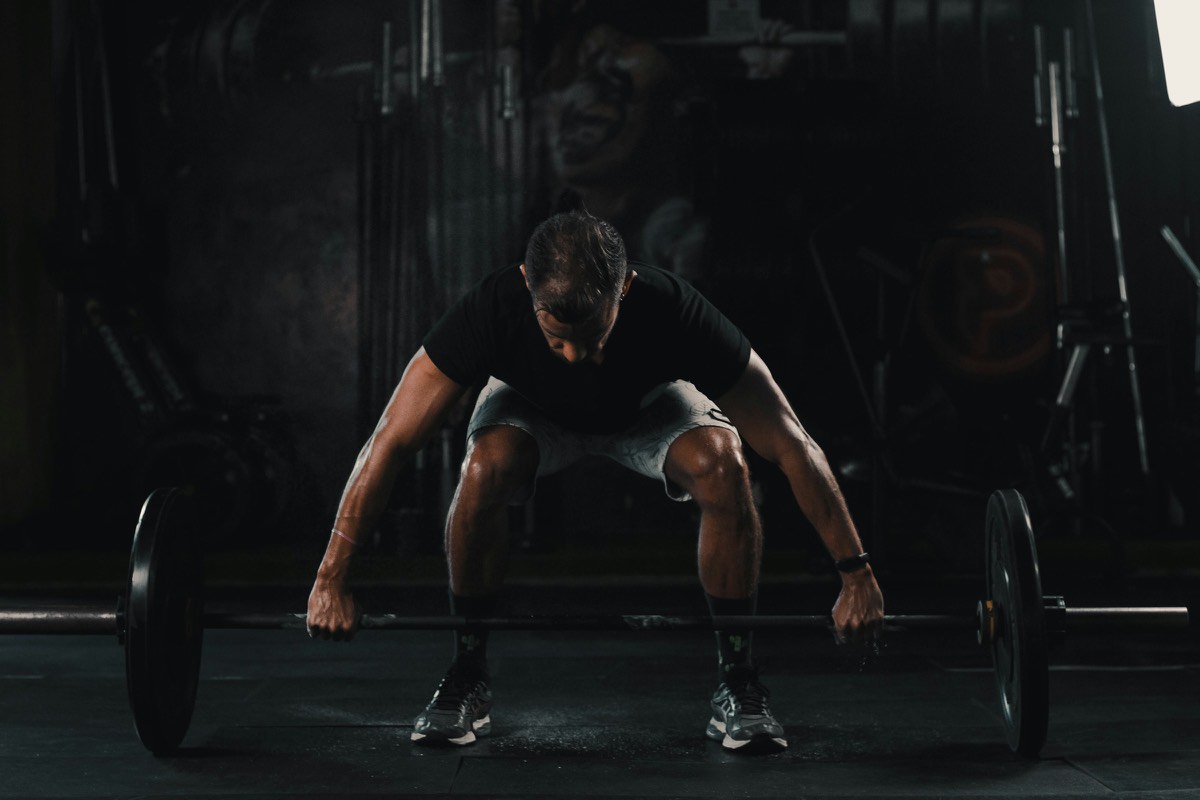Atleta preparando un peso muerto en un gimnasio oscuro