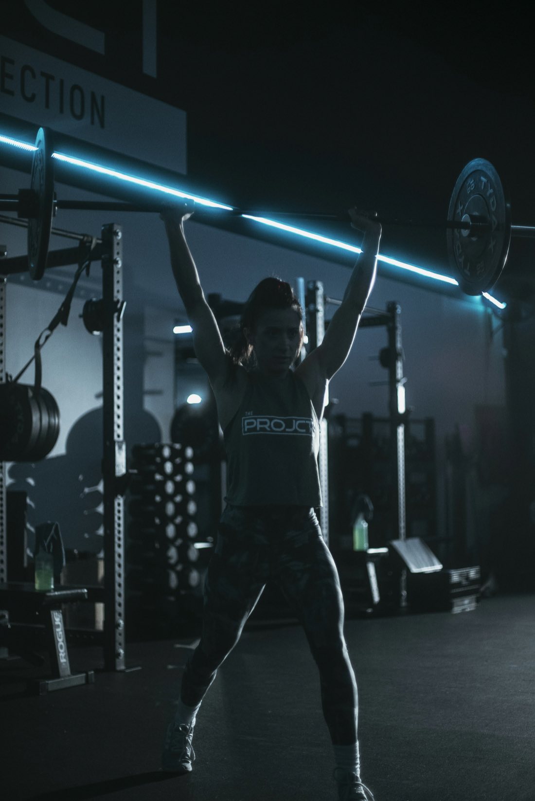 Atleta levantando una barra sobre la cabeza con luz dramática